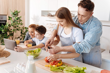 Pleasant loving father giving her daughter cooking lessons