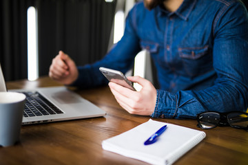 close up hands multitasking man using laptop and cellphone connecting wifi, notebook and coffee cup