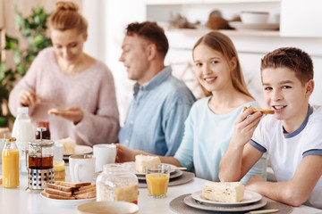Obraz na płótnie Canvas Cheerful boy having breakfast with his friendly family