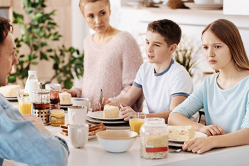 Obraz na płótnie Canvas Confused girl having breakfast with her family