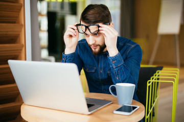 Business man with glasses having eyesight problems confused with laptop isolated on office background.