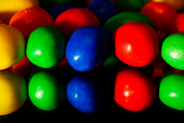 Colorful candy on black background with mirror reflection