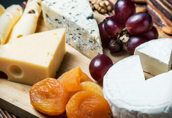 Cheese plate with fruits and nuts on a wooden table