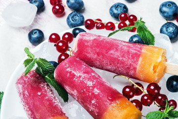 Sorbet on a stick of red currant and blueberries on a wooden table
