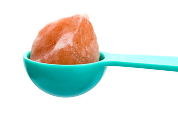Closeup of Himalayan pink rock salt on a Cyan spoon. Isolated over white background