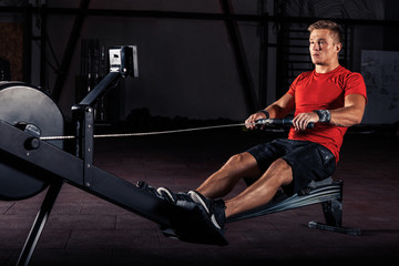Fototapeta na wymiar young man using rowing machine in the gym