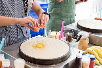 Woman's hand making crispy crape. Street food of Thailand.