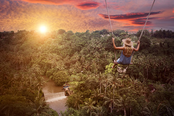 Adventure in wild jungle forest. Woman on swing.