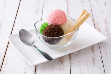 Ice cream scoops in crystal bowl on white wooden background. 

