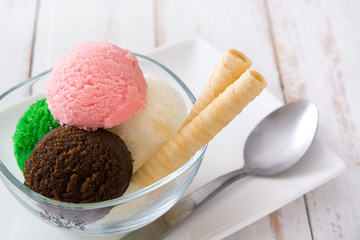 Ice cream scoops in crystal bowl on white wooden background. 
