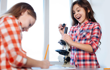 Emotional clever child exploring construction of a microscope