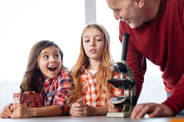 Emotional curious kids fascinated about using a microscope