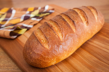 Freshly baked wheat loaf on a cutting board closeup