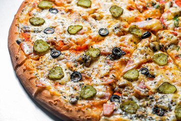 pizza with sausage and pickles, by cut to pieces on a metal table. selective focus on the filling close-up.