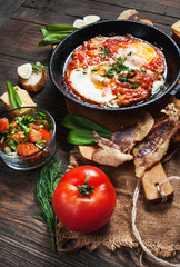 fried eggs with bacon in a pan close-up on wood background