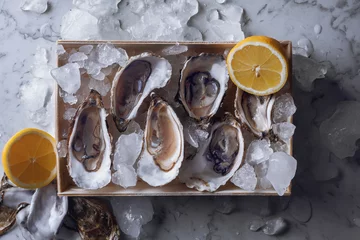 Papier Peint photo Lavable Crustacés Oyster box with ice and lemon over a gray marble table