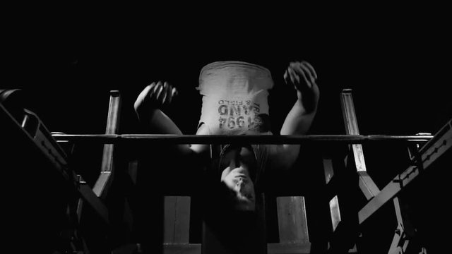 Black-and-white shot of handsome athletic man starting bench pressing