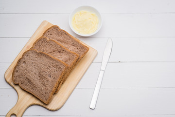 Close-up of slice of toast bread with butter on wood table