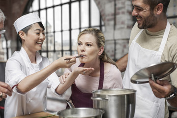 Female student tasting from pot in cooking class