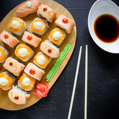 Japanese food - sushi rolls, sauce and chopsticks on a black background. Top view. Flat lay. Restaurant food.