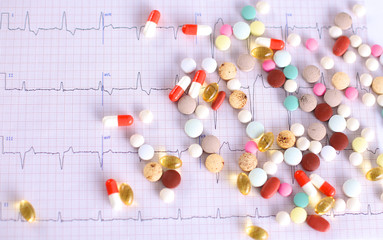 Colored pills lie on a paper cardiogram