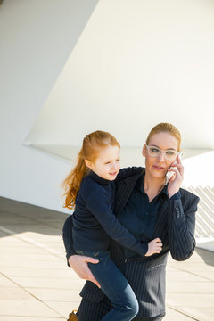 Businesswoman on the phone holding daughter