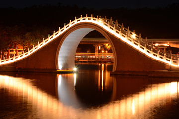 Traditional Chinese bridge and reflection over Dahu Park lake at night in Taipei, Taiwan