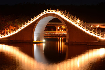Fototapeta na wymiar Traditional Chinese bridge and reflection over Dahu Park lake at night in Taipei, Taiwan