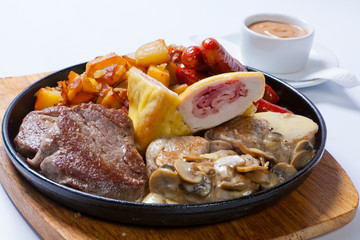 grilled sausages with potatoes, mushrooms and roasted chicken on a grill pan