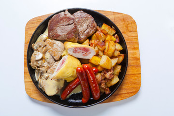 grilled sausages with potatoes, mushrooms and roasted chicken on a grill pan