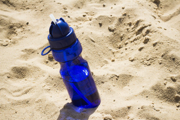 Blue sport water bottle in the sand