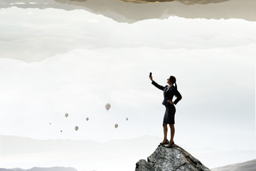 Businesswoman catching moment on her mobile . Mixed media