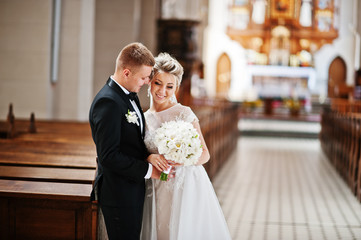 Photosession of stylish wedding couple on catholic church.