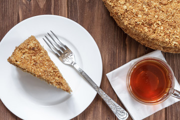 Round cake napoleon with tea on a wooden background.