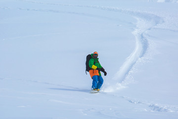 Fototapeta na wymiar snowboarder snowboarding on fresh snow on ski slope on Sunny winter day in the ski resort in Georgia
