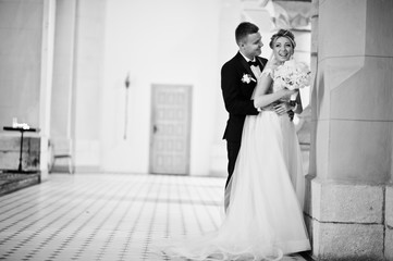 Photosession of stylish wedding couple on catholic church.