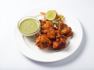 Chicken tikka with pudina chutney served in a white plate 