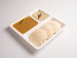 idli with sambar and coconut chutney served in a white plate on white background