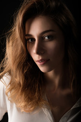 close up studio portrait of young woman in white blouse on black background