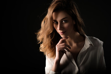 close up studio portrait of young smiling woman in white blouse on black background