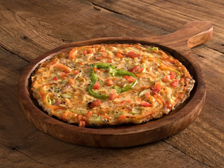Mixed vegetables pizza served in a wooden plate on wooden background