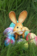 Colored Easter eggs and rabbit on green grass background