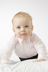 Fototapeta premium Close-up portrait of cute 9-month-old toddler looking at camera. Adorable crawling infant kid.