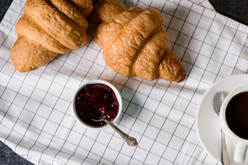 Picture of croissants , pot with jam and coffee cup aside on grey table