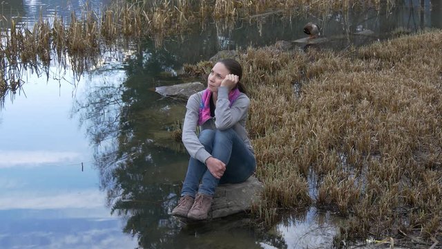 Woman sitting near pond and dreaming