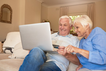 Fototapeta premium Happy seniors shopping online from their living room sofa