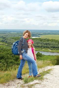 Adult and child standing on a mountaintop near  river.  Family hiking in mountains on vacation