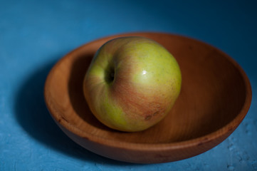 green apple in wooden plate on old blue background table