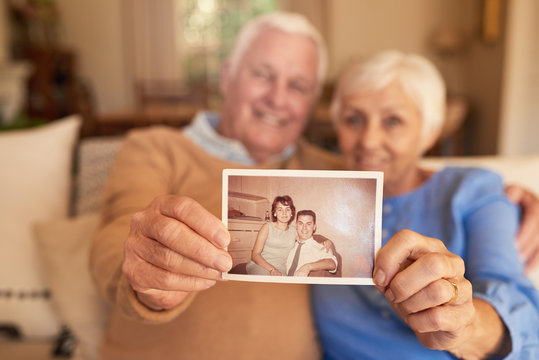 Content Senior Couple Holding A Photo Of Their Youthful Selves 