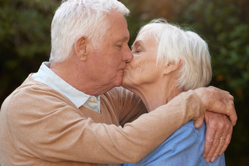 Affectionate seniors in love hugging and kissing outdoors